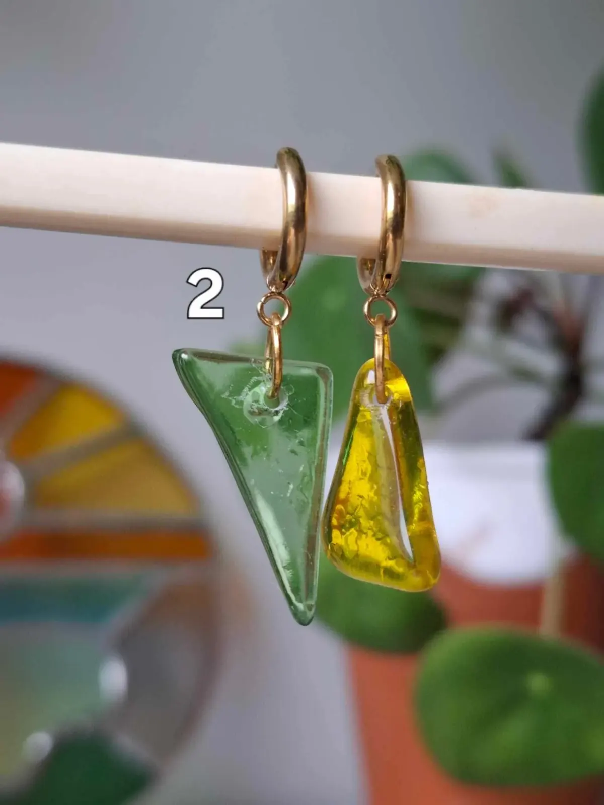 Créoles dorées avec pendants asymétriques en verre translucide vert et jaune de formes triangulaires.
