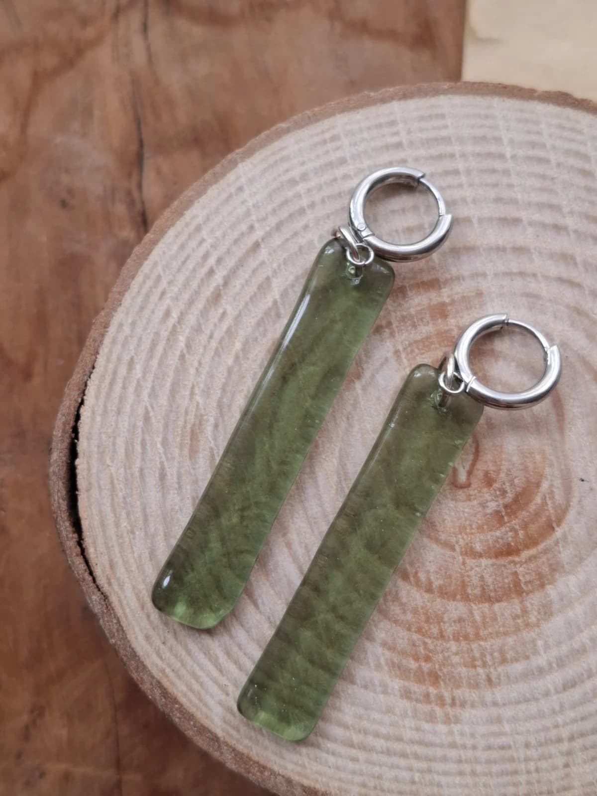 Paire de boucles d'oreilles pendantes rectangulaires vertes suspendue à une tige fine.