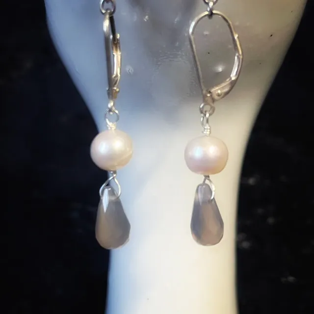 Boucles d'oreilles pendantes Arista avec perles d'eau douce et agates suspendues sur un support en céramique.