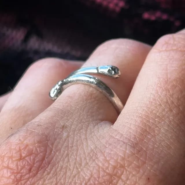 Vue de profil de la bague ouverte en métal argenté sculptée en forme d'allumette.