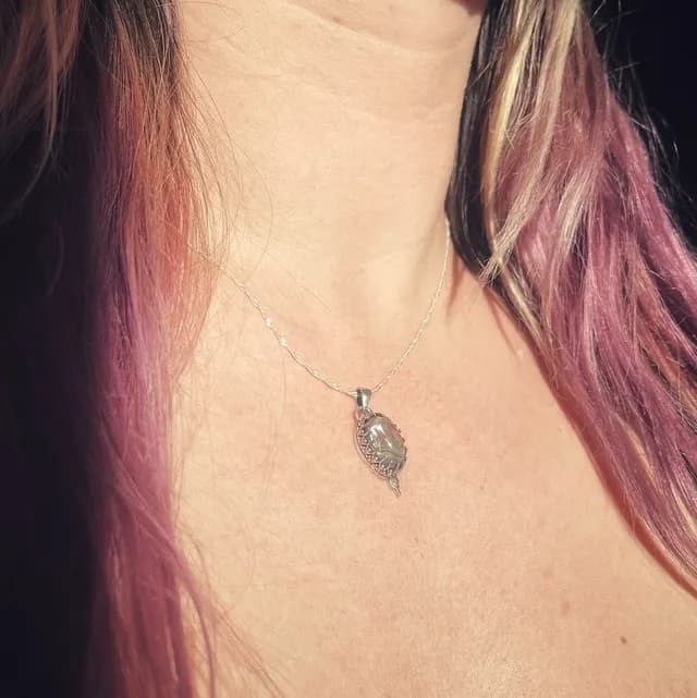 Collier Nox et son pendentif ovale en argent vus de trois-quarts portés au décolleté.