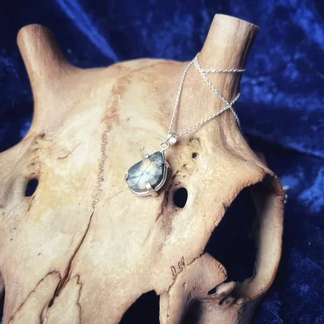 Collier et pendentif en pierre taillée présentés sur un support organique naturel.