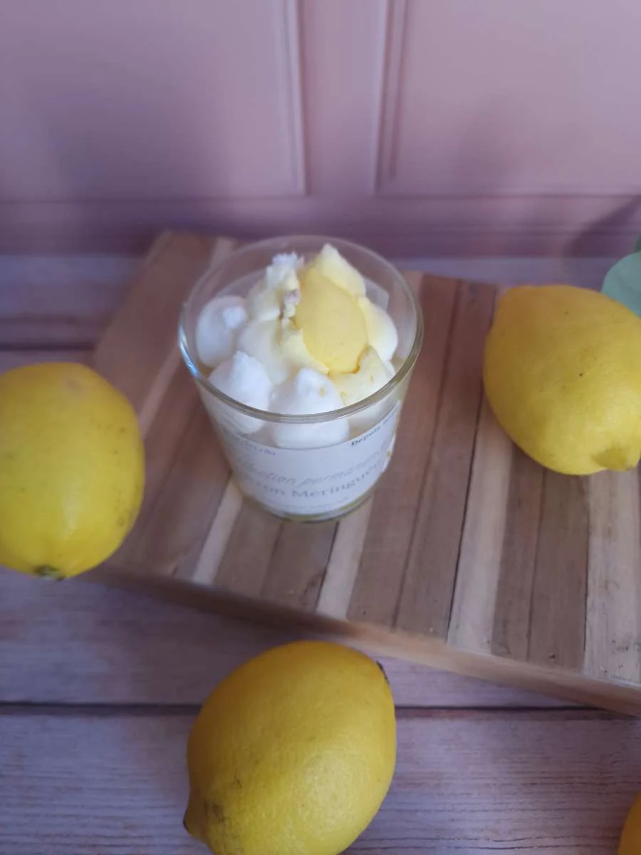 Vue plongeante sur la cire jaune et blanche effet meringue dans un verre transparent entouré de citrons.
