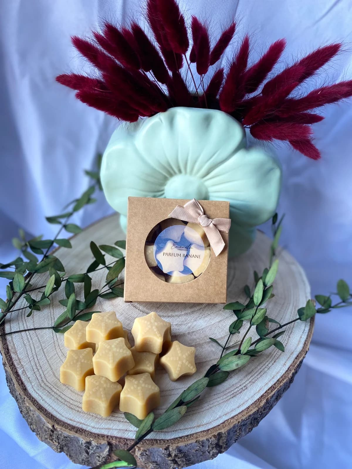 Coffret kraft et fondants parfumés en forme d'étoiles sur rondin de bois décoré de feuillage