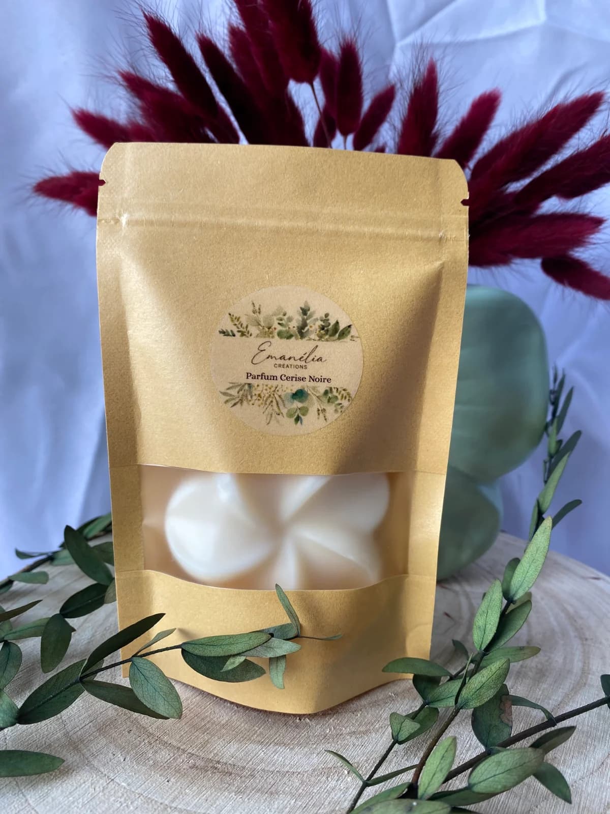 Sachet de fondant parfumé posé sur une tranche de bois au décor végétal.